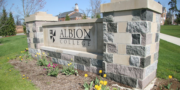 Albion College sign on the southeastern part of campus, with Ferguson Hall (left) and the Kellogg Center in the background.