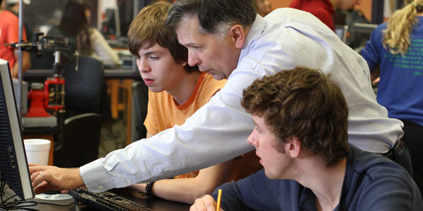 Professor David Seely works with students in a physics lab.