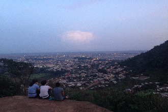 Students sit on the top of a hill overlooking the town.  