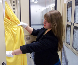 Ouendag holds a dress worn by Betty Ford while working in the storage area of the Ford Museum.