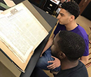 Nathan Kellum, '19 (top), and Shane Mills, '19 look at pages of The Liberator, a 19th-century abolitionist newspaper, at a library in Philadelphia, summer 2018. 