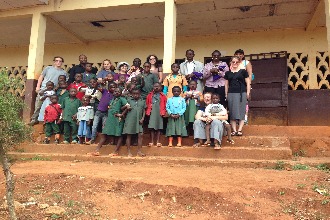 Students on the steps of a building with local children. 